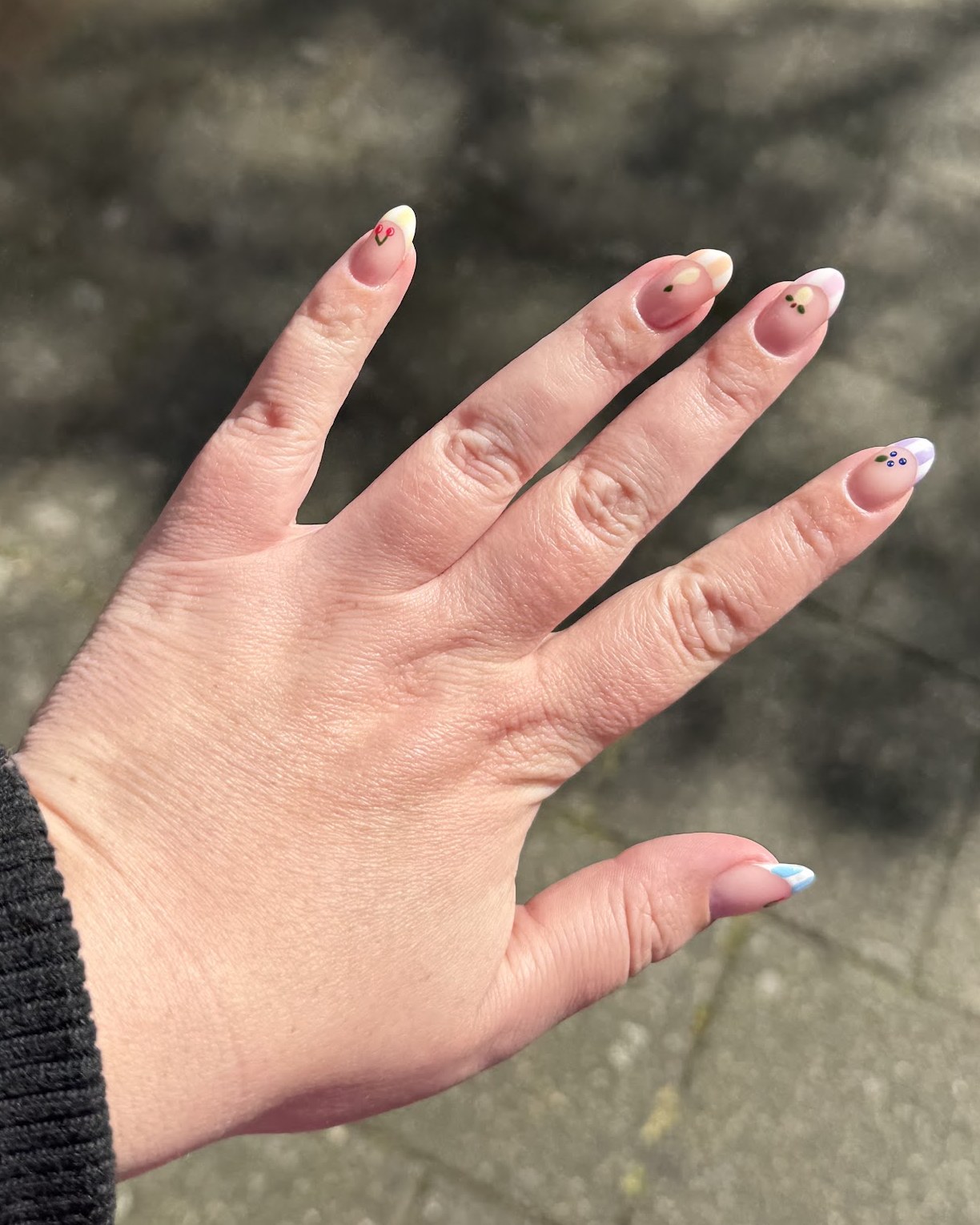 Korte pastel nagels met kleine stipjes en een lichtblauw puntje